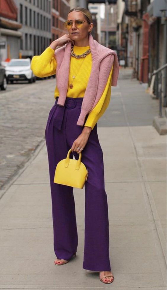 persona che posa per mostrare il suo outfit colorato fatto di viola e di giallo