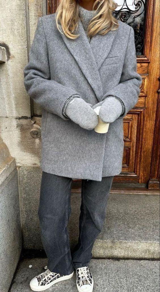 Donna che indossa una giacca invernale di colore grigio con guanti. BLOG