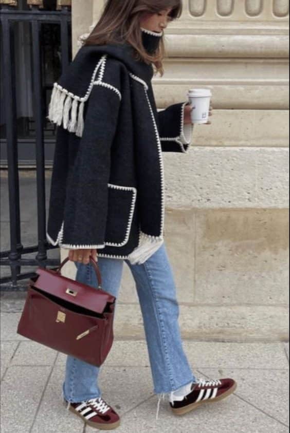 ragazza che passeggia in outfit invernale con jeans e scarpe e borsa borgogna