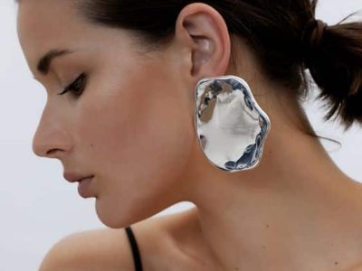 modella di profilo con indosso degli orecchi globulari argento